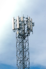 Cell tower with antennas against a cloudy sky
