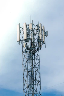 Cell tower with antennas against a cloudy sky