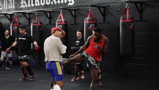 Men training kickboxing in a gym with punching bags.