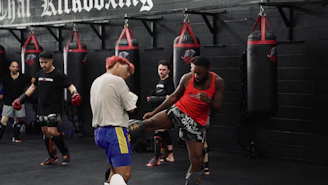 Men training kickboxing in a gym with punching bags.