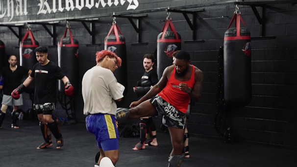 Men training kickboxing in a gym with punching bags.