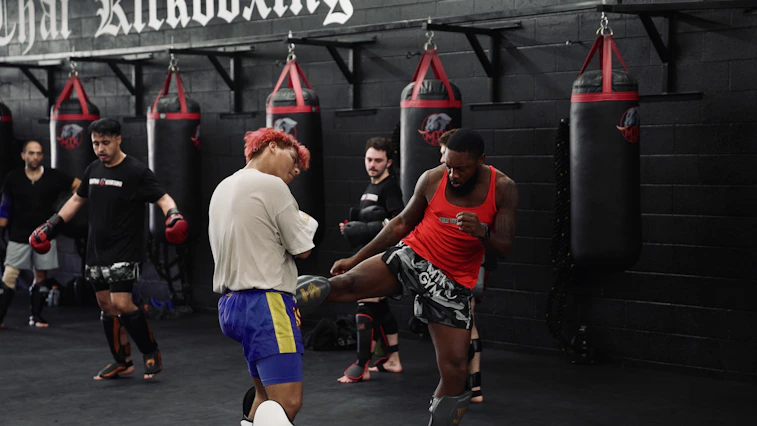 Men training kickboxing in a gym with punching bags.