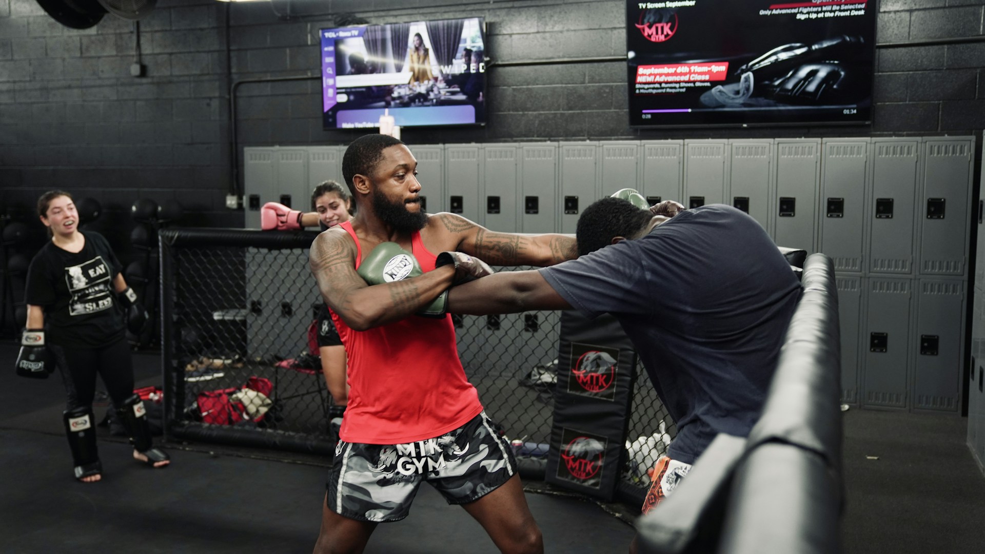 Two men sparring in a boxing gym with spectators.