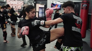 Woman kicks man during muay thai training session
