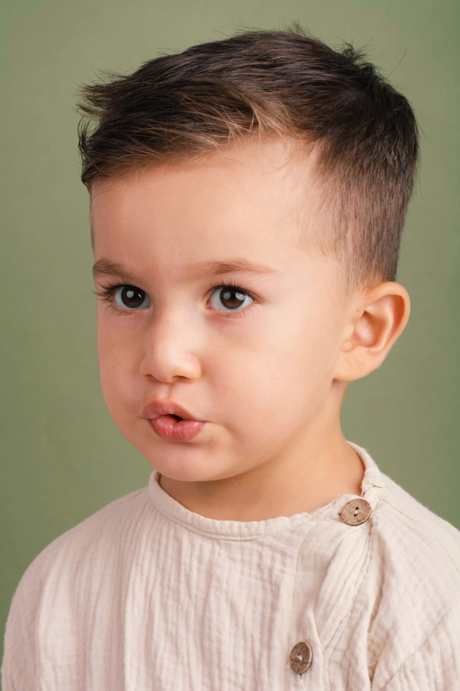 A young boy with a freshly cut and styled haircut, looking to one side.