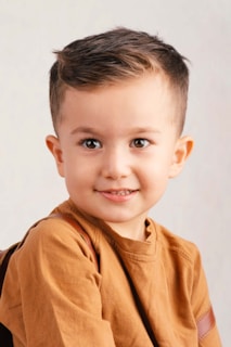 A young boy with brown hair and brown eyes smiles.