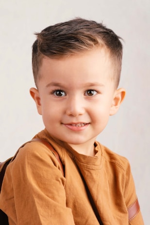 A young boy with brown hair and brown eyes smiles.