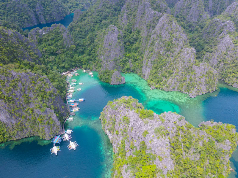 Boats anchored in a turquoise lagoon surrounded by limestone cliffs