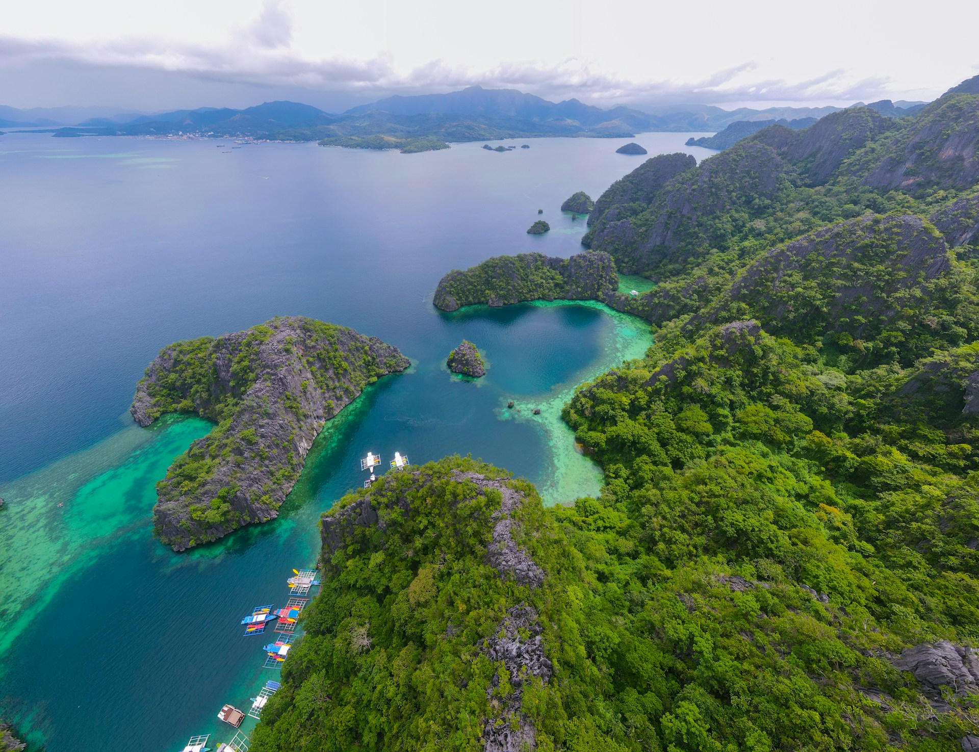 Lush green islands surrounded by turquoise waters and boats.