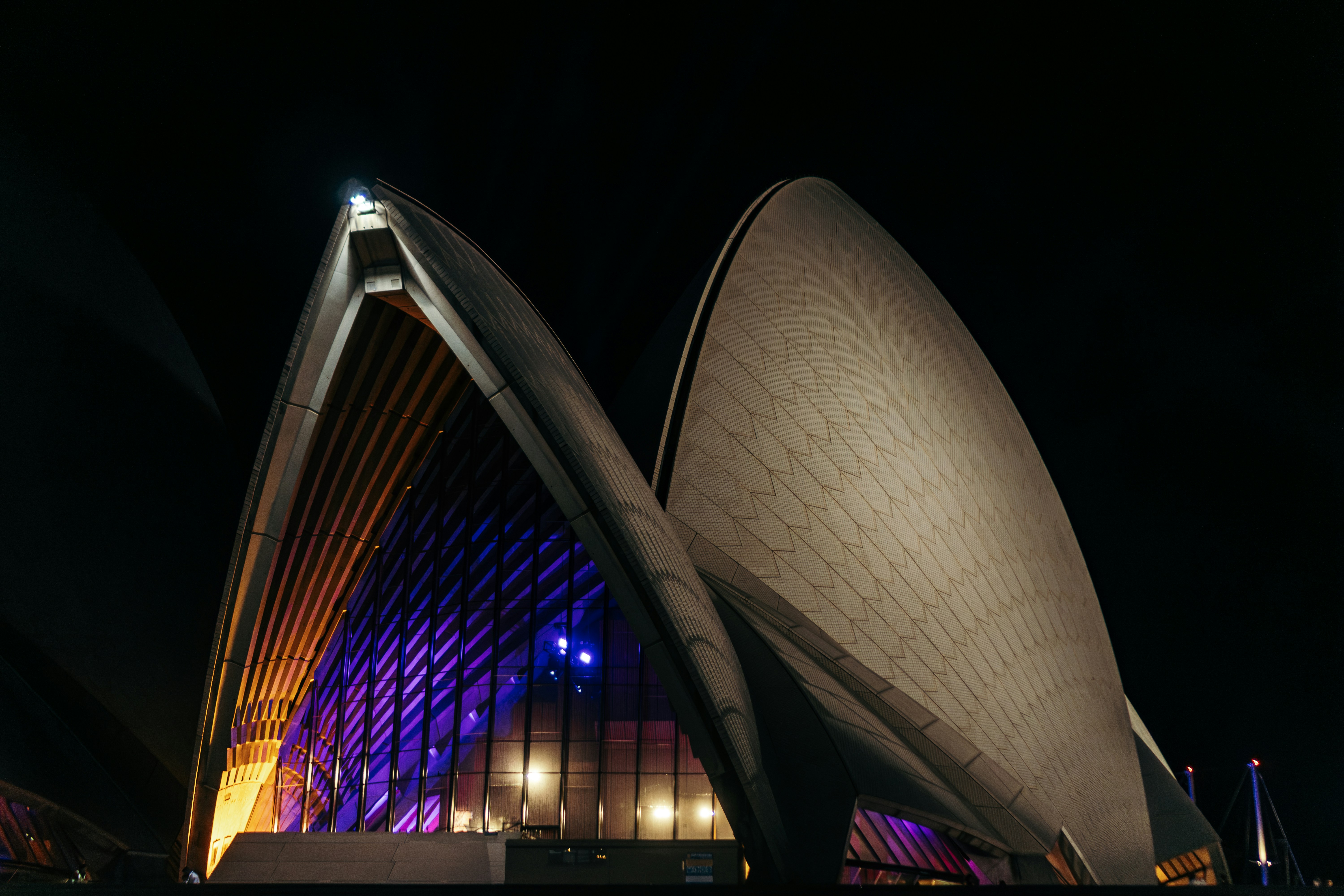 Sydney opera house illuminated at night with colorful lights
