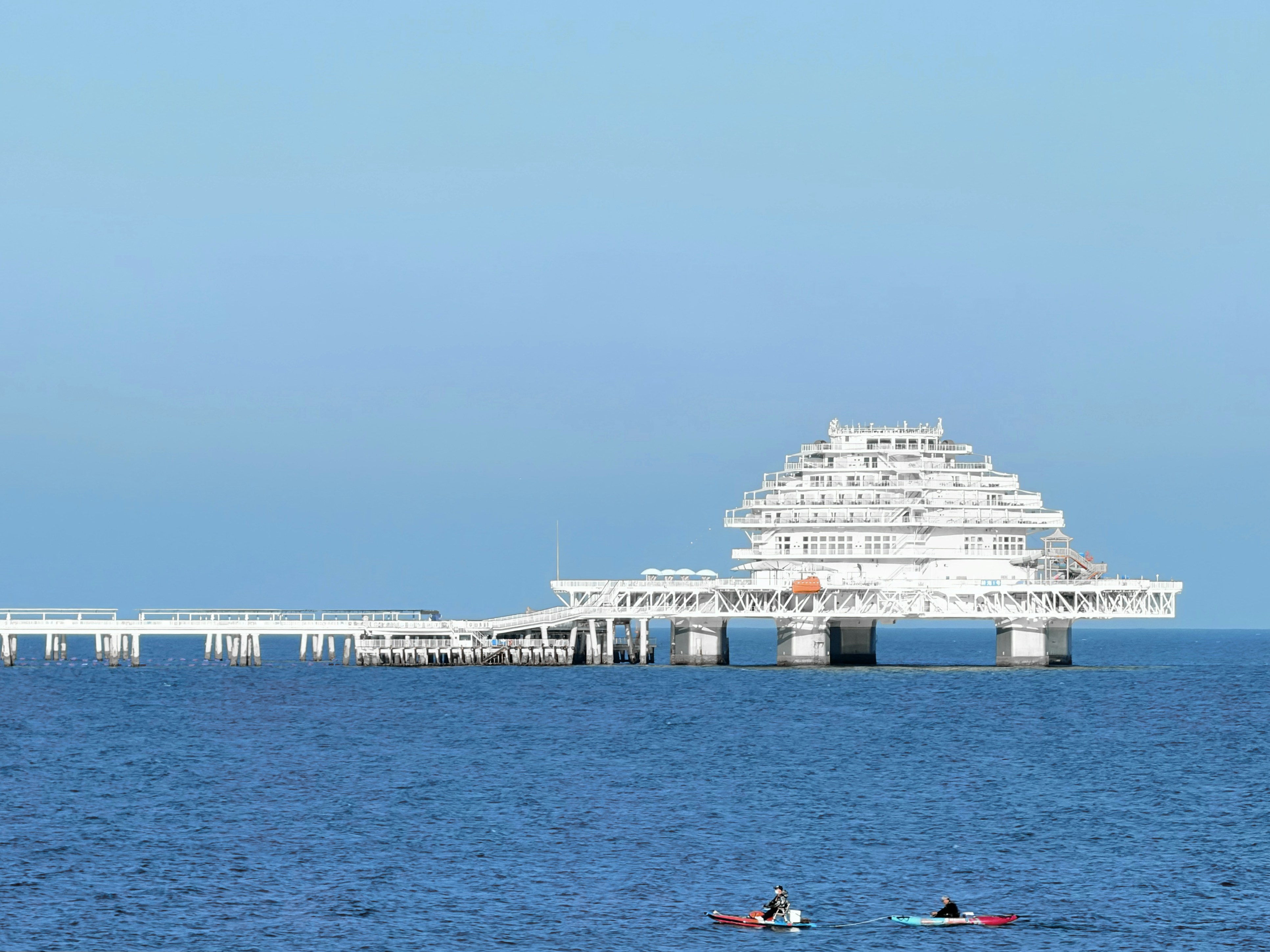 Weißes Gebäude auf Stelzen über dem Meer