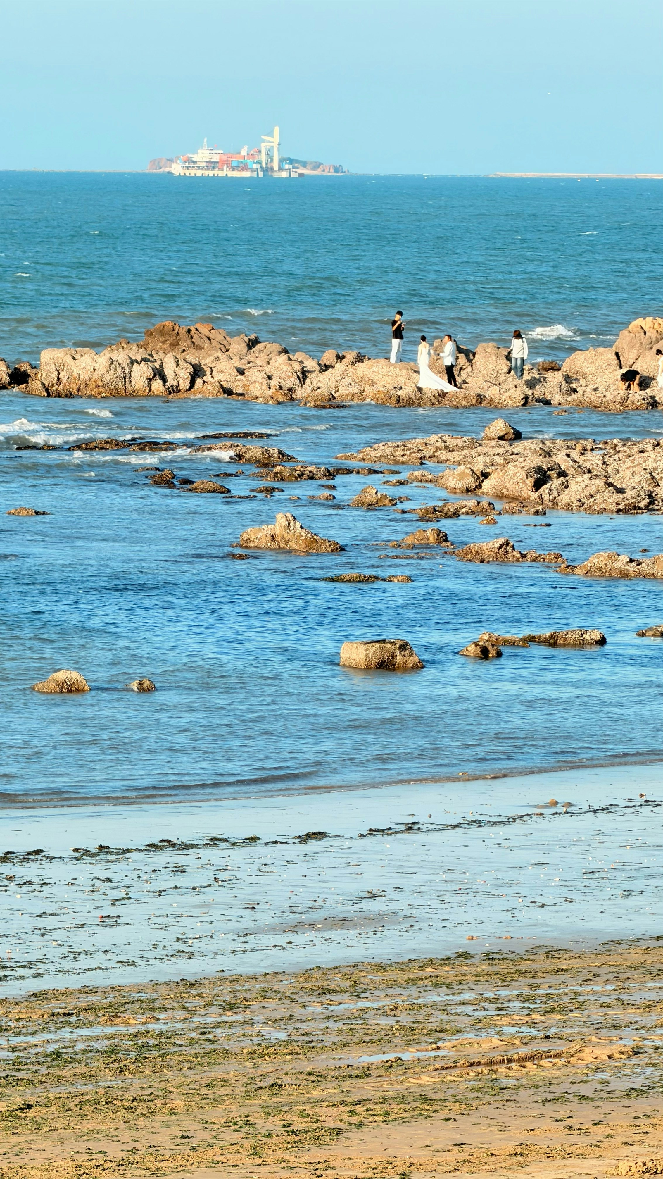 Menschen auf Felsen mit Ozean und entfernten Gebäuden.