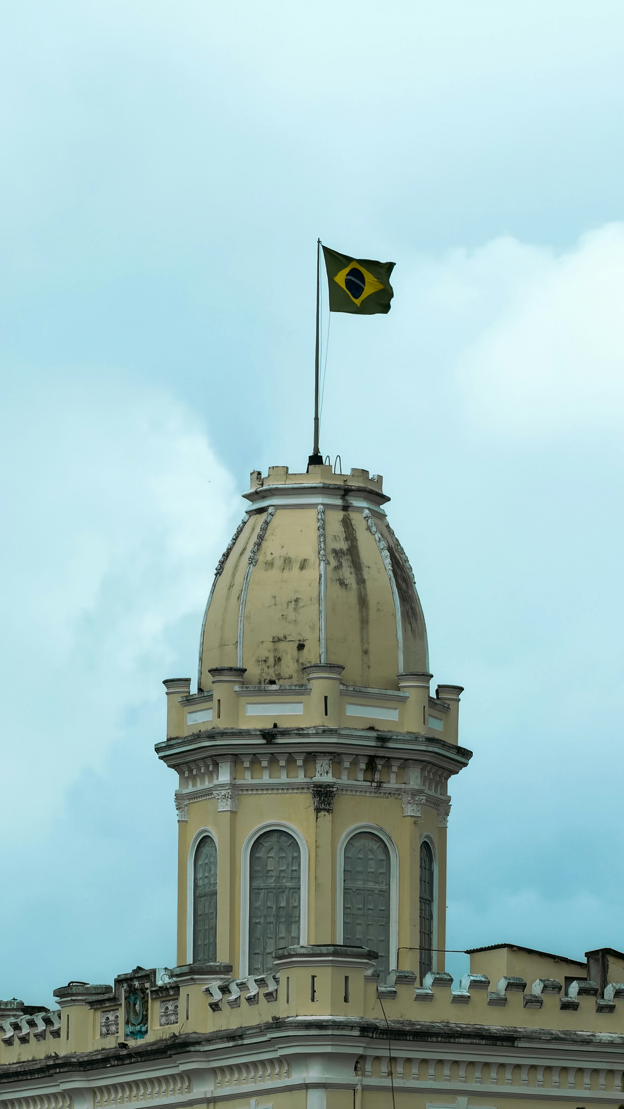 Brazilian flag flies atop a yellow dome building.