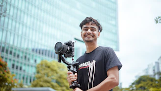 Man holding camera on gimbal in front of building