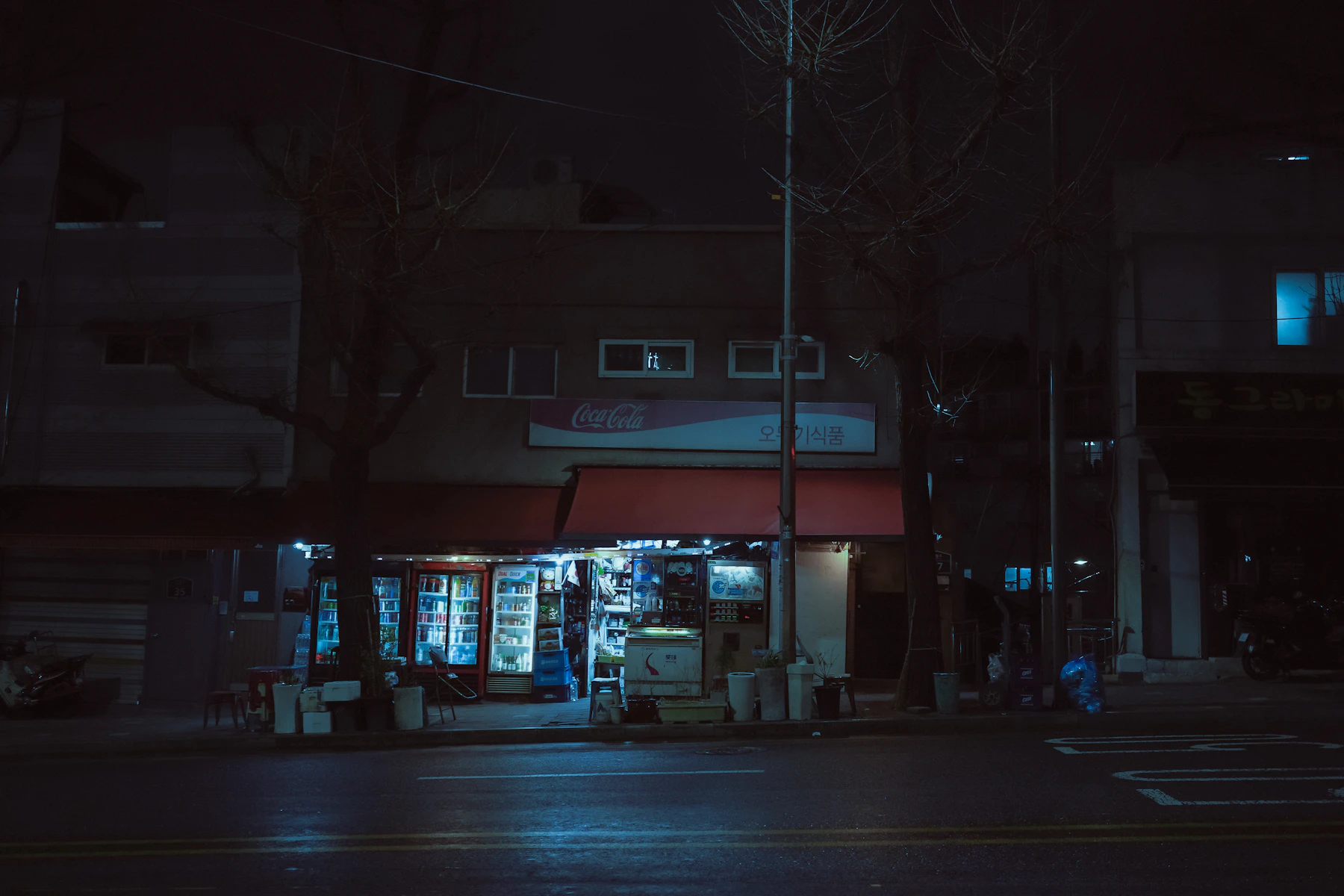 A small corner store lit up on a dark, empty street at night