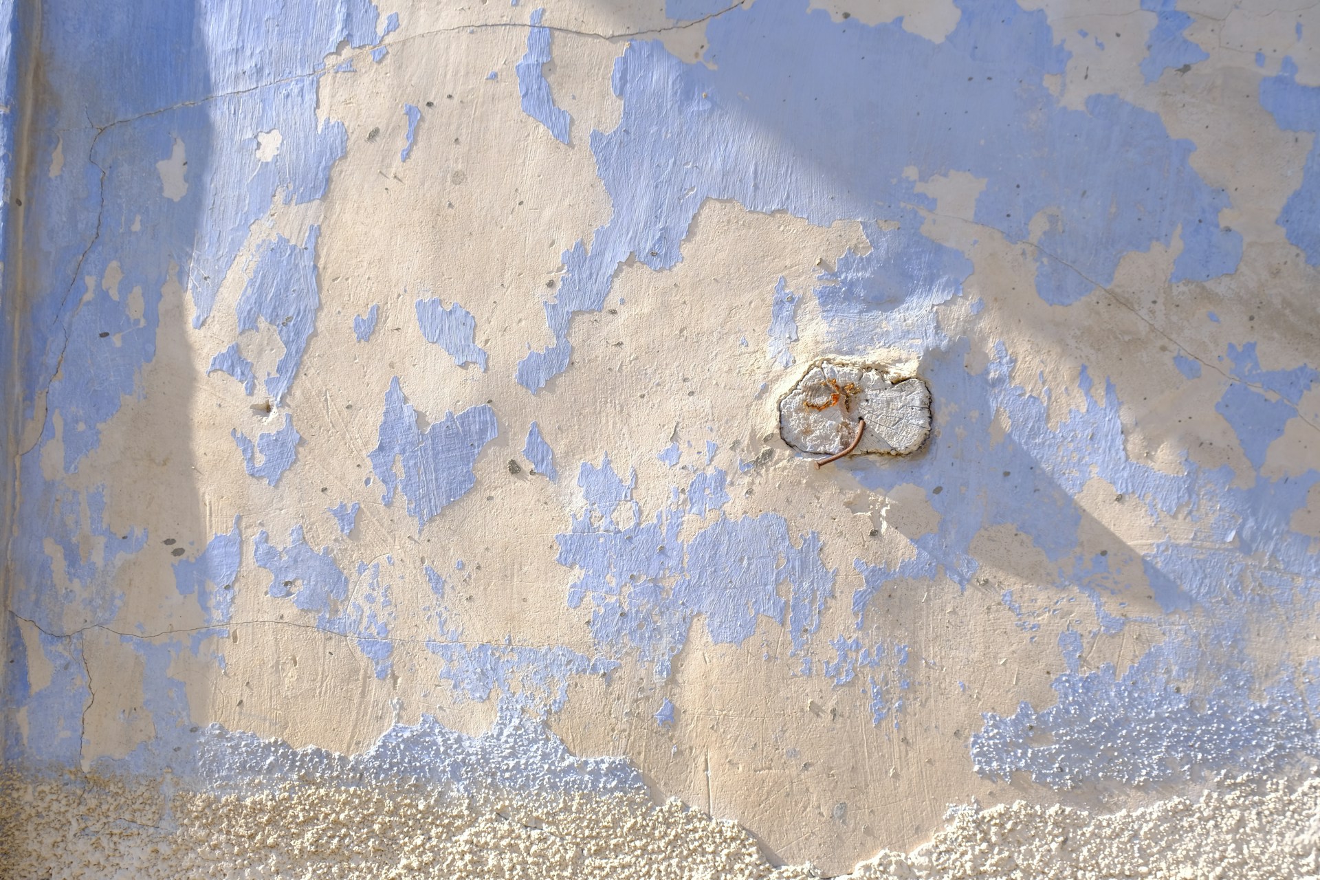 Peeling blue paint on a textured wall