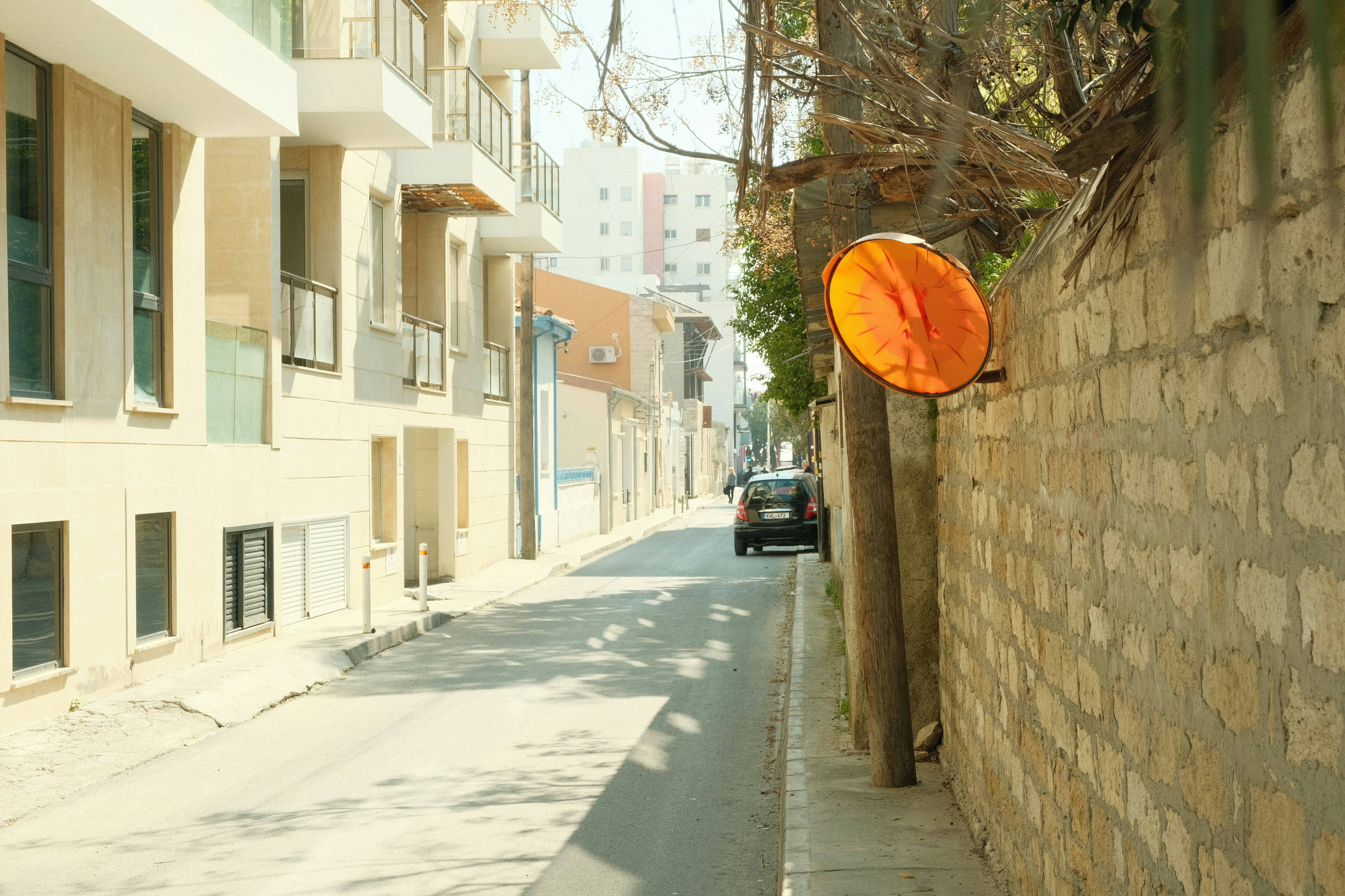 A narrow street with buildings and a traffic mirror.