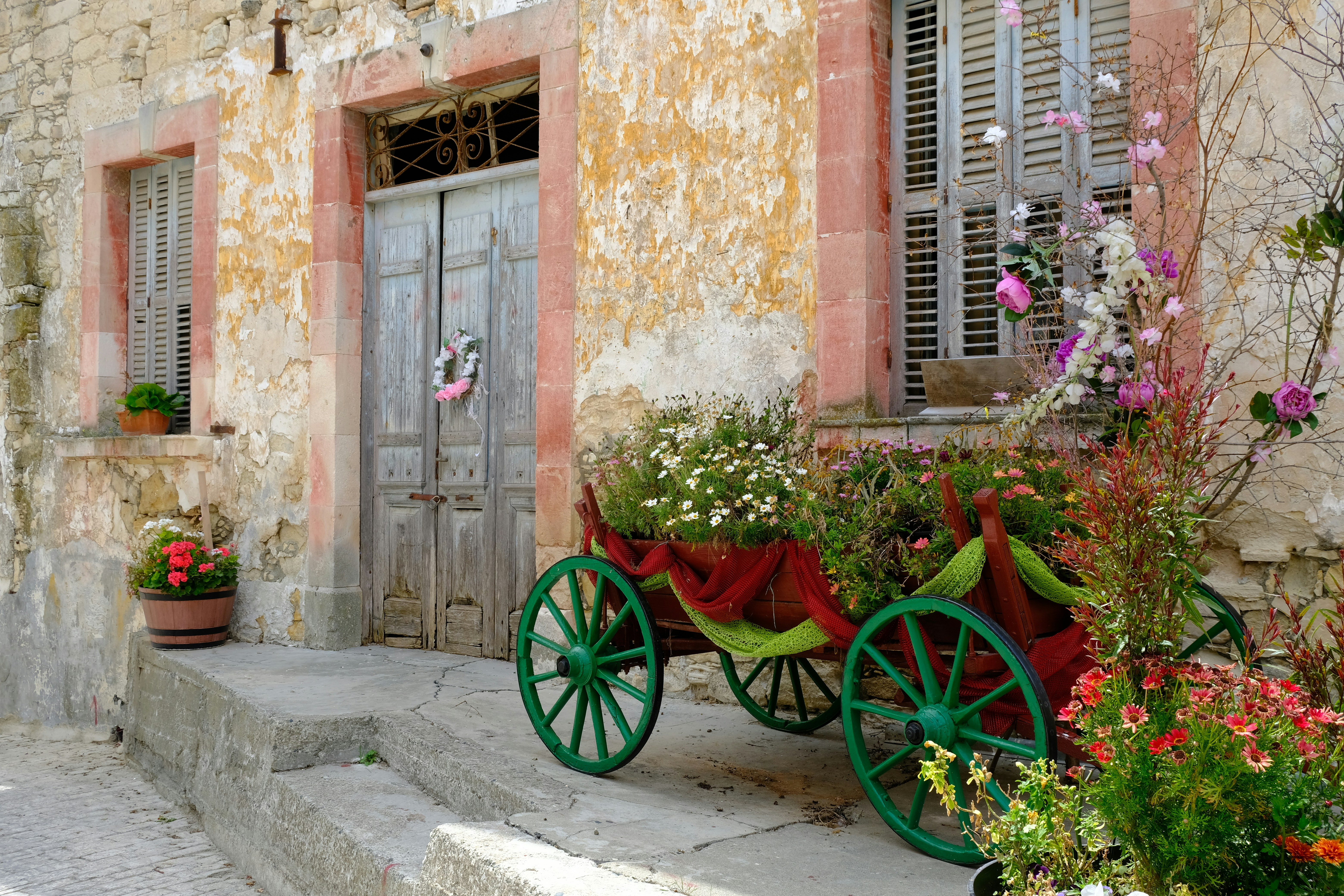 Decorative wagon filled with flowers outside old building