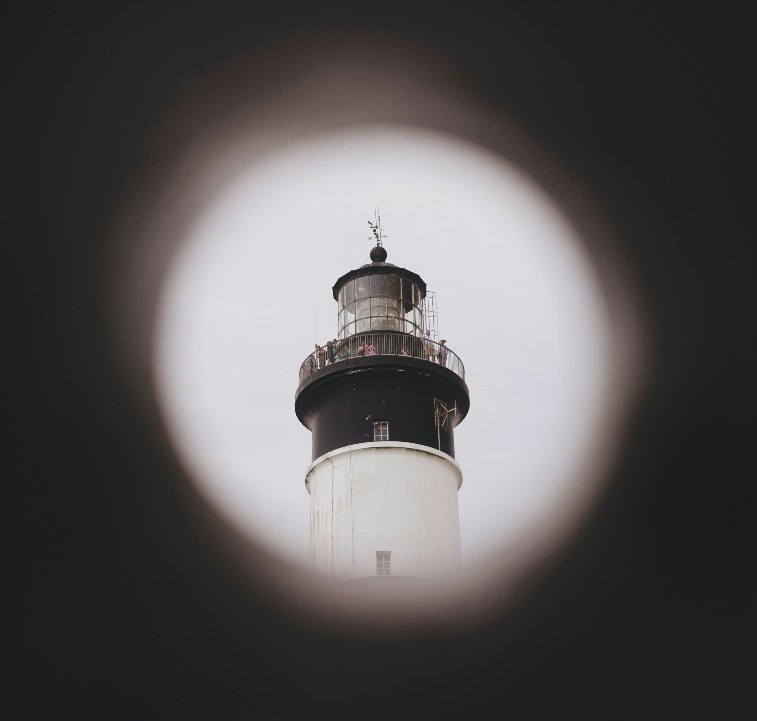 Lighthouse viewed through a dark circular frame.