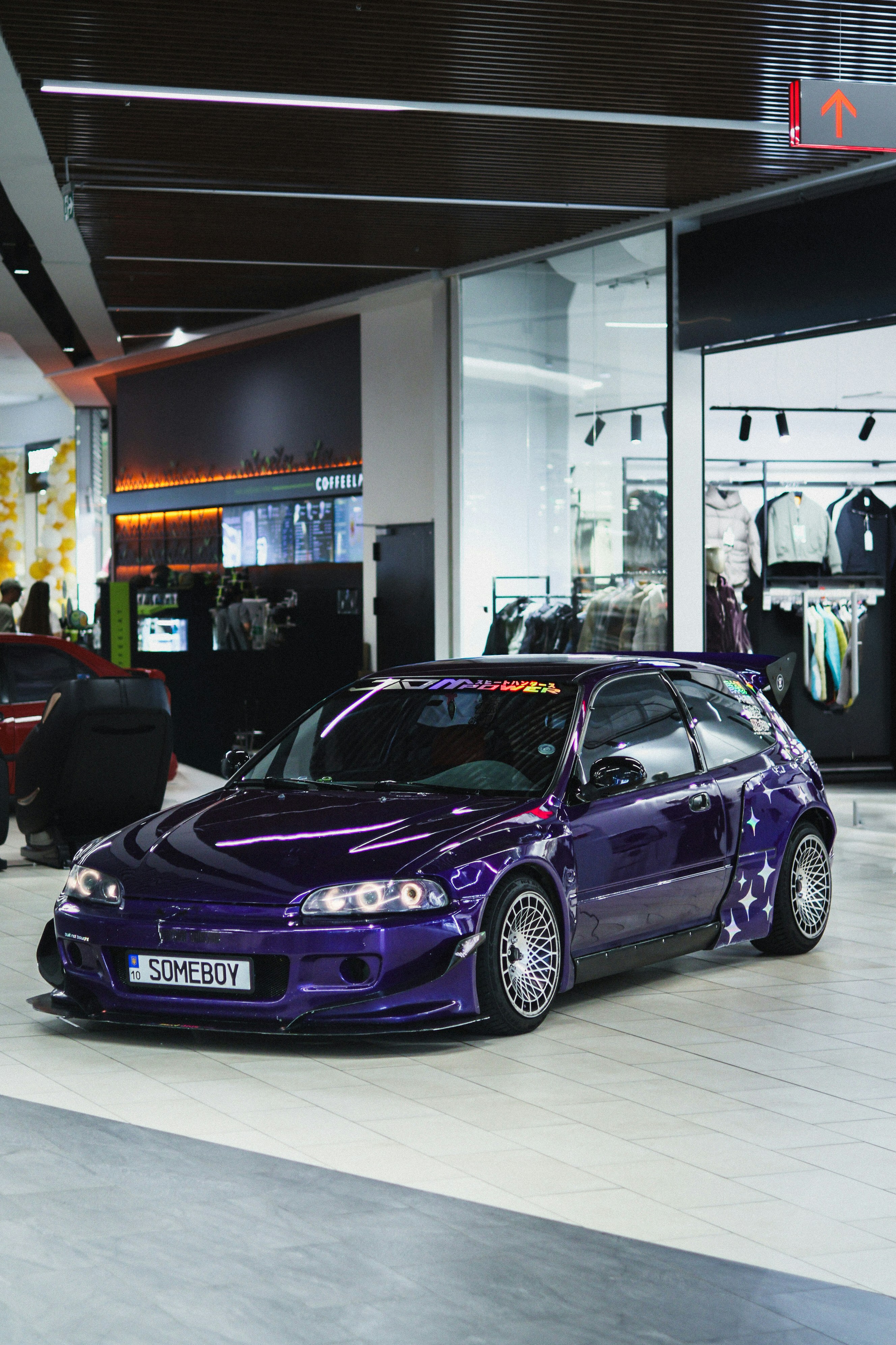 A custom purple honda civic hatchback parked indoors.