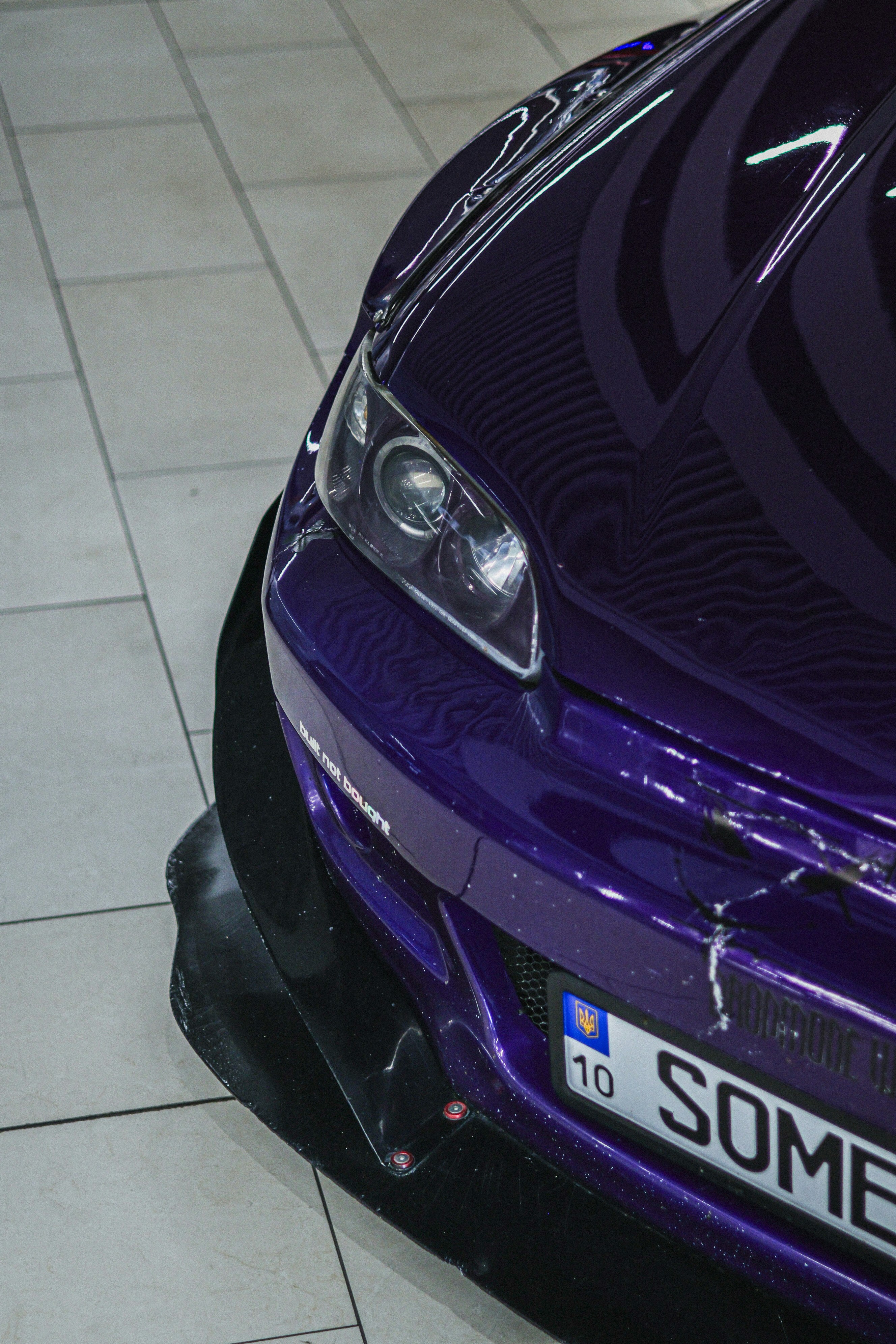 Close-up of a shiny purple car with a license plate.