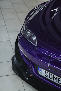 Close-up of a shiny purple car with a license plate.