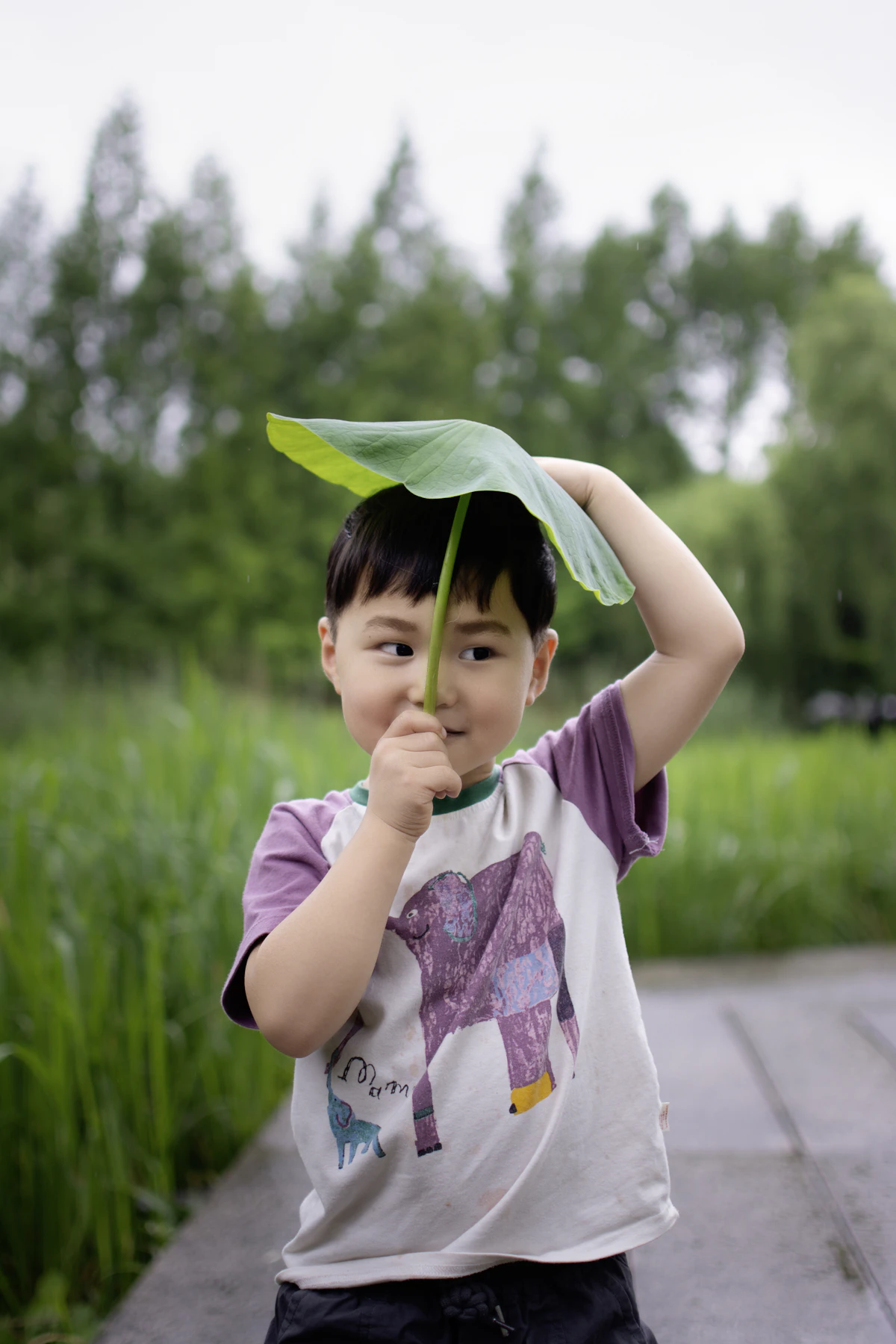 Toddler on a nature scavenger hunt for toddlers, holding a large leaf outdoors