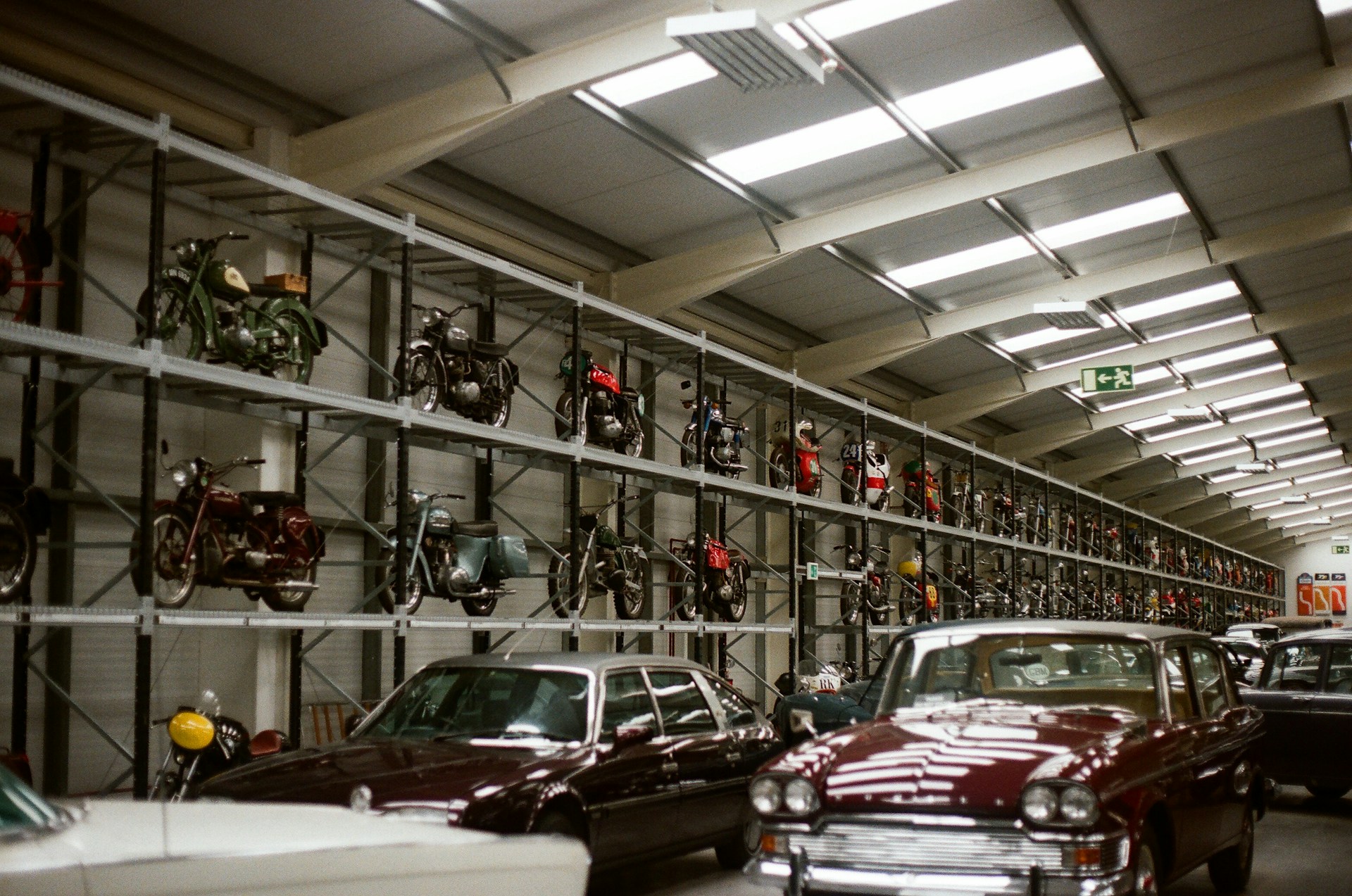 Vintage cars and motorcycles displayed in a large garage.