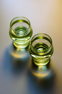 Two glasses of green liquid with reflections