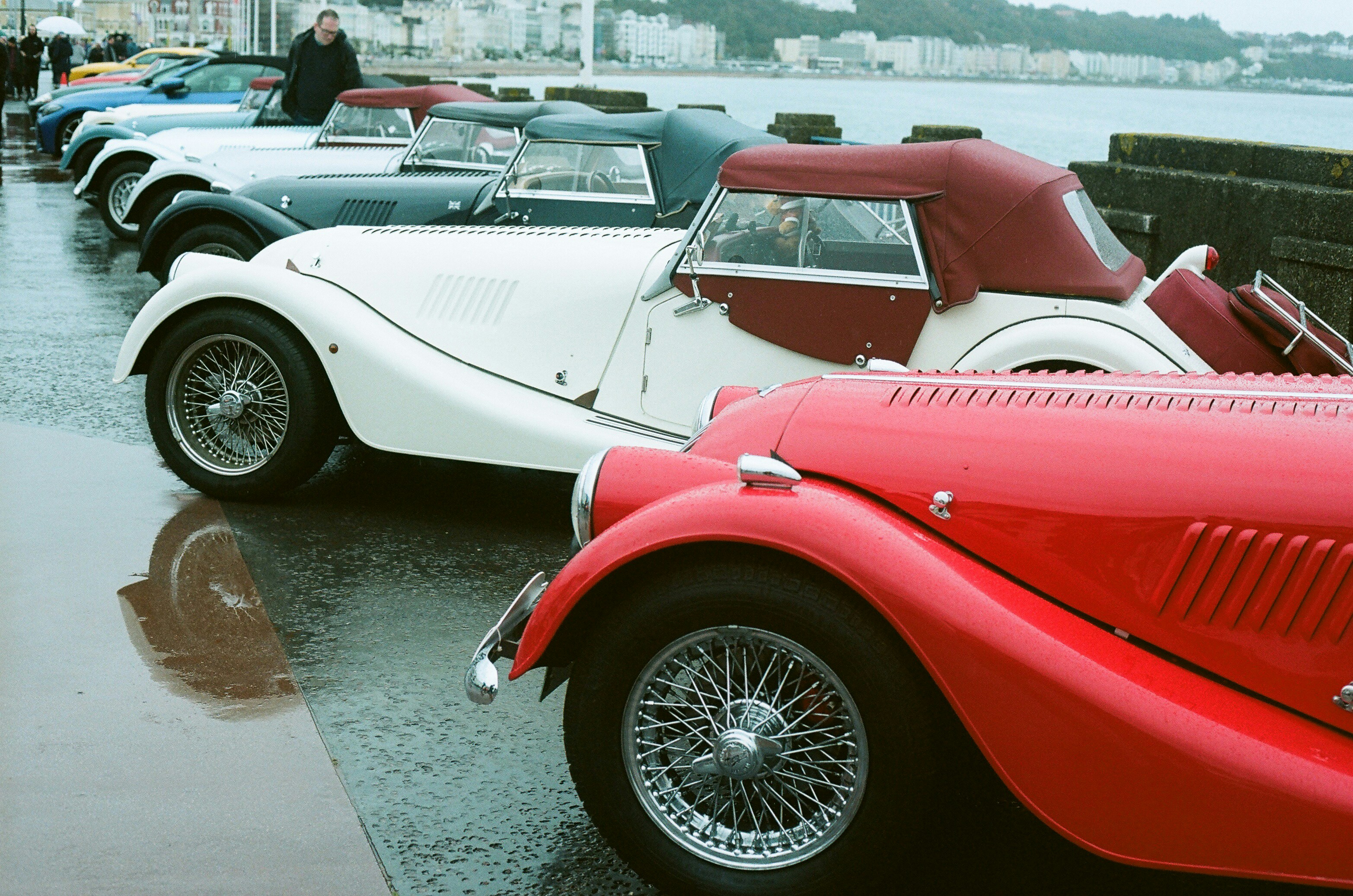 Row of classic convertible cars parked by the water