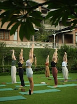 Women practicing yoga outdoors on a grassy lawn.