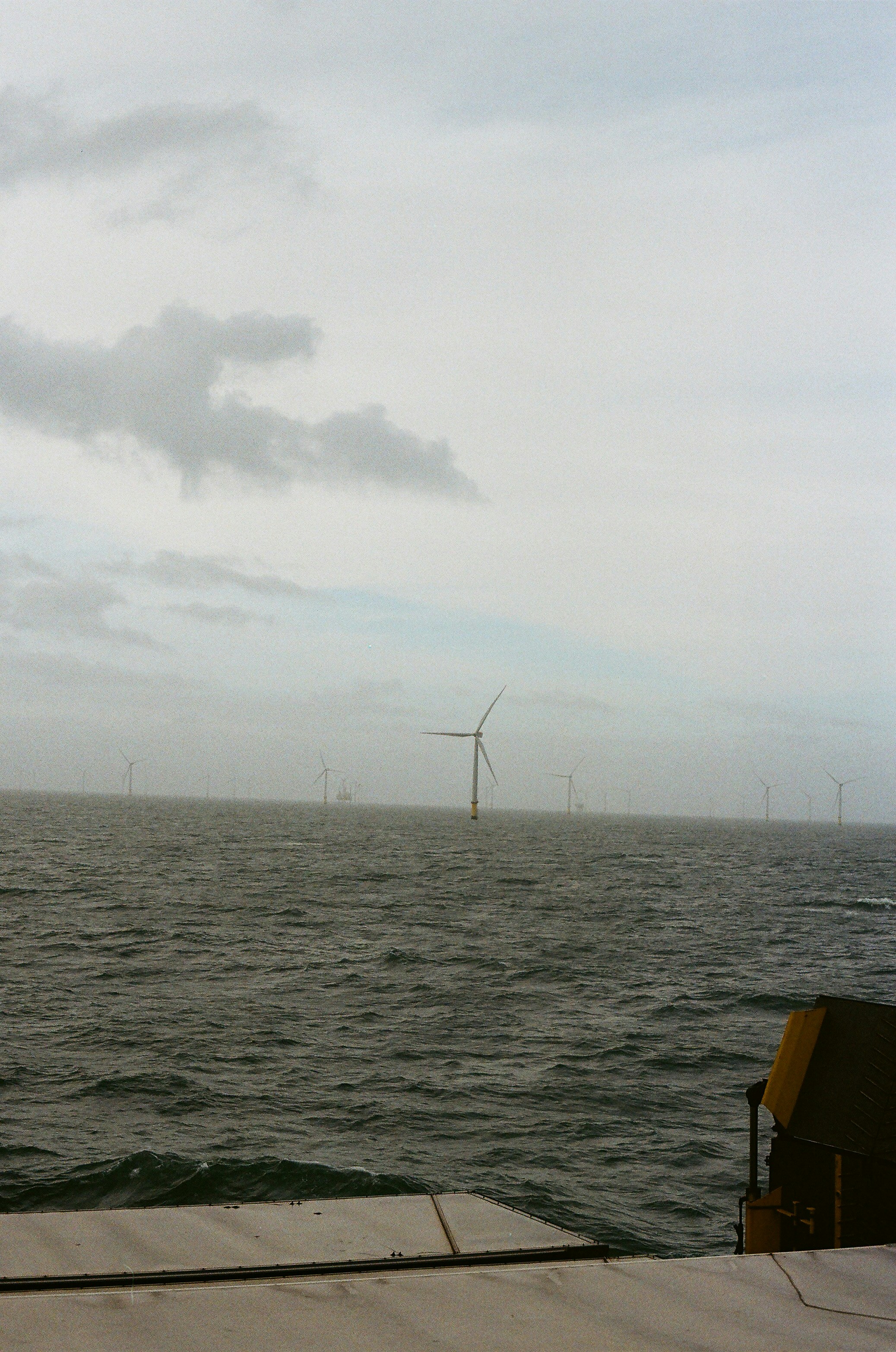 Wind turbines in the ocean under a cloudy sky.