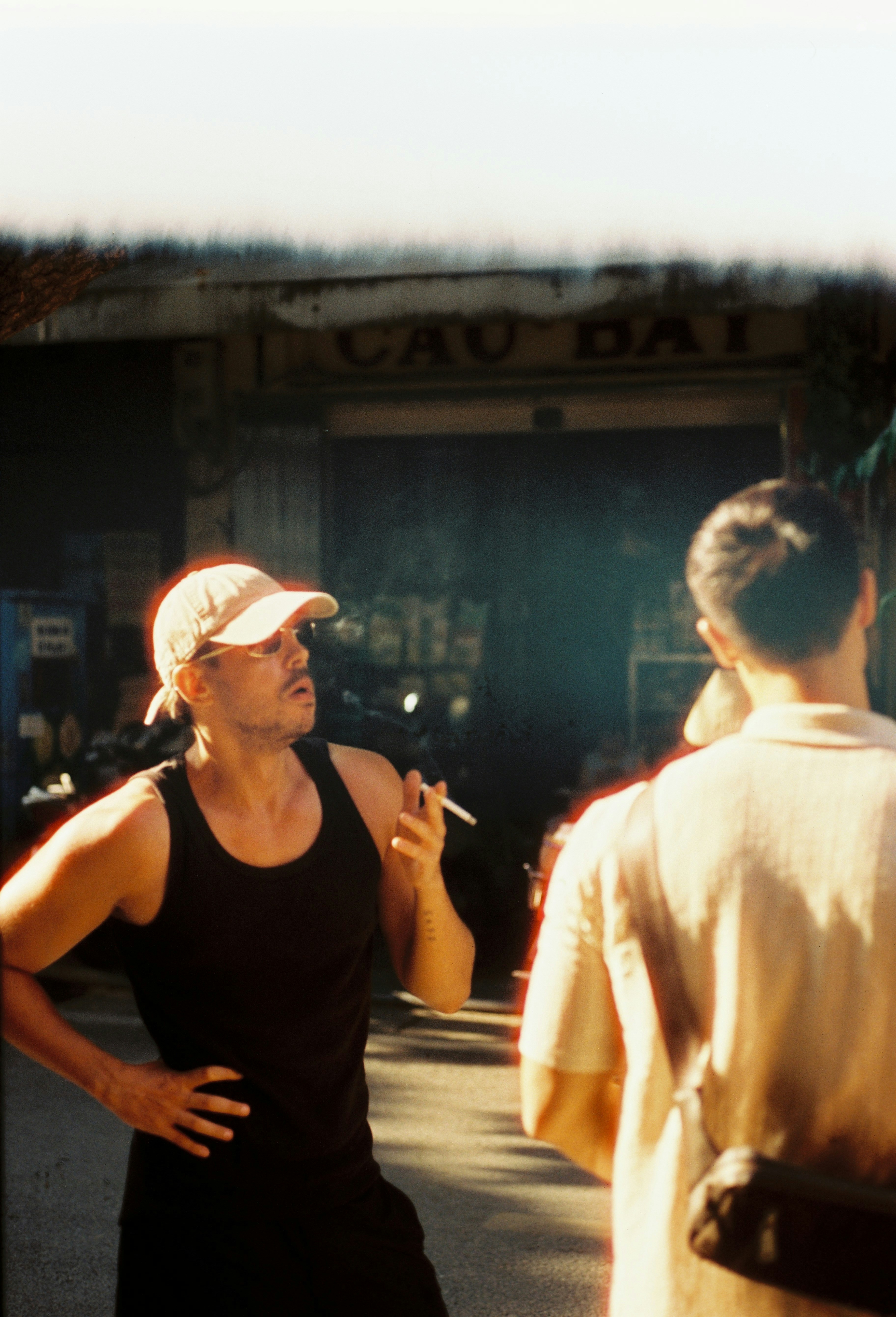 Hombre con camiseta sin mangas y gorra fumando cigarrillos al aire libre.  foto – Imagen de Conversación gratuita en Unsplash, image size:3000x4408