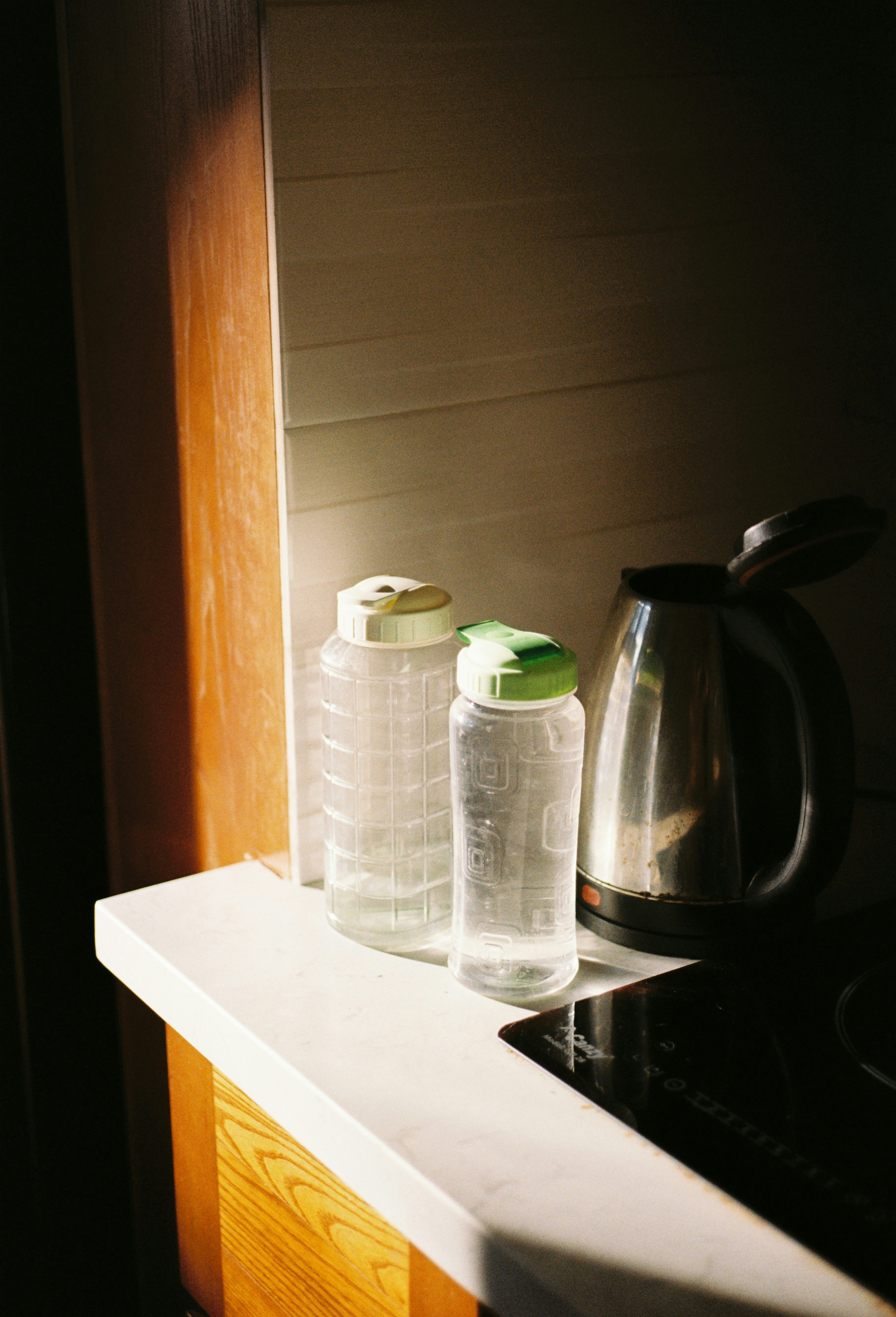 Two water bottles and kettle on counter.