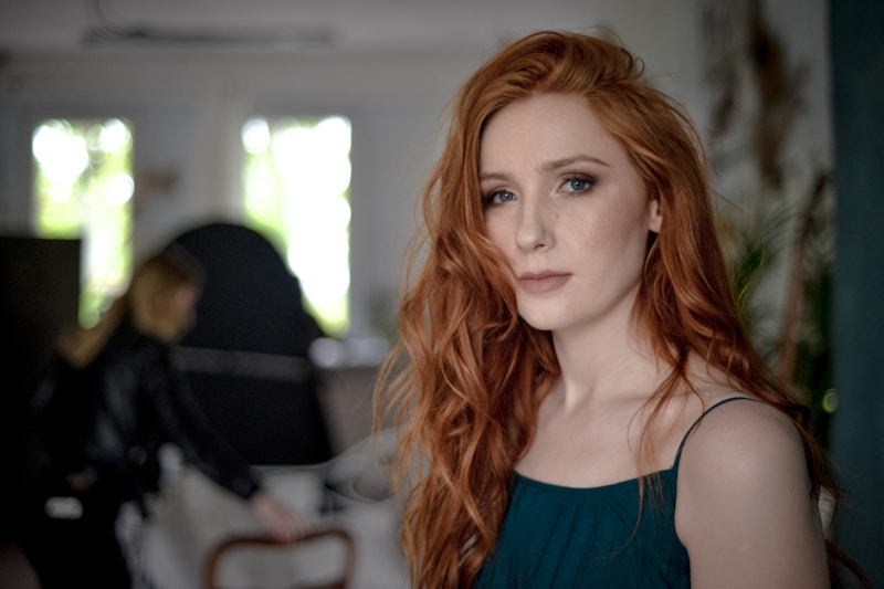 A woman with long, wavy red hair indoors.