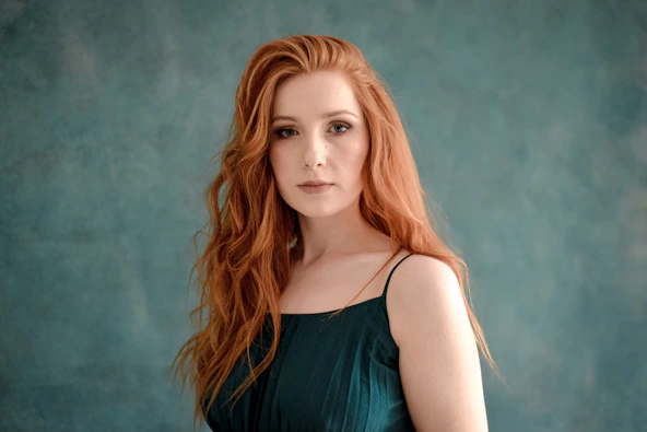 Young woman with long red hair and green dress.