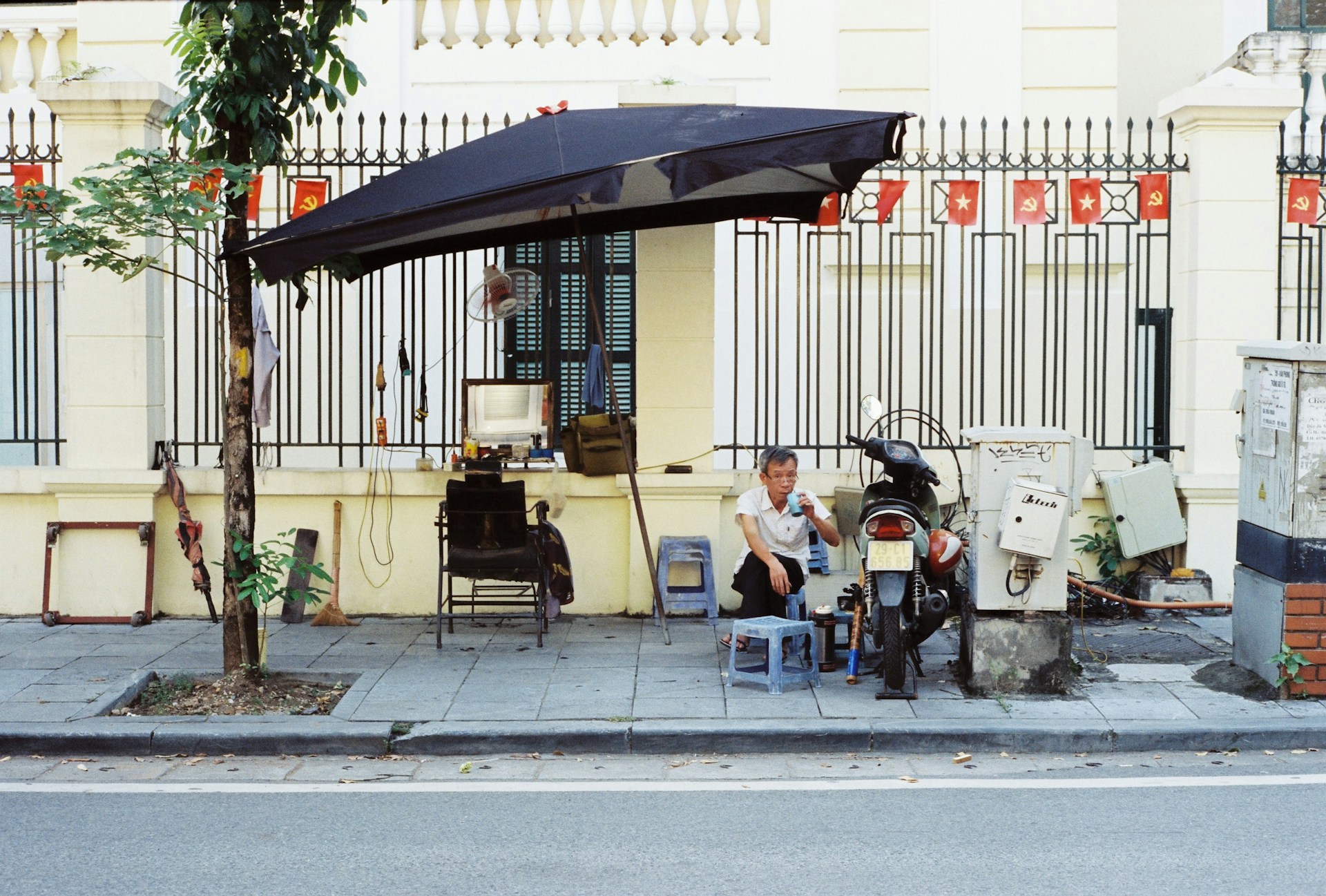Man sitting under umbrella next to motorcycle