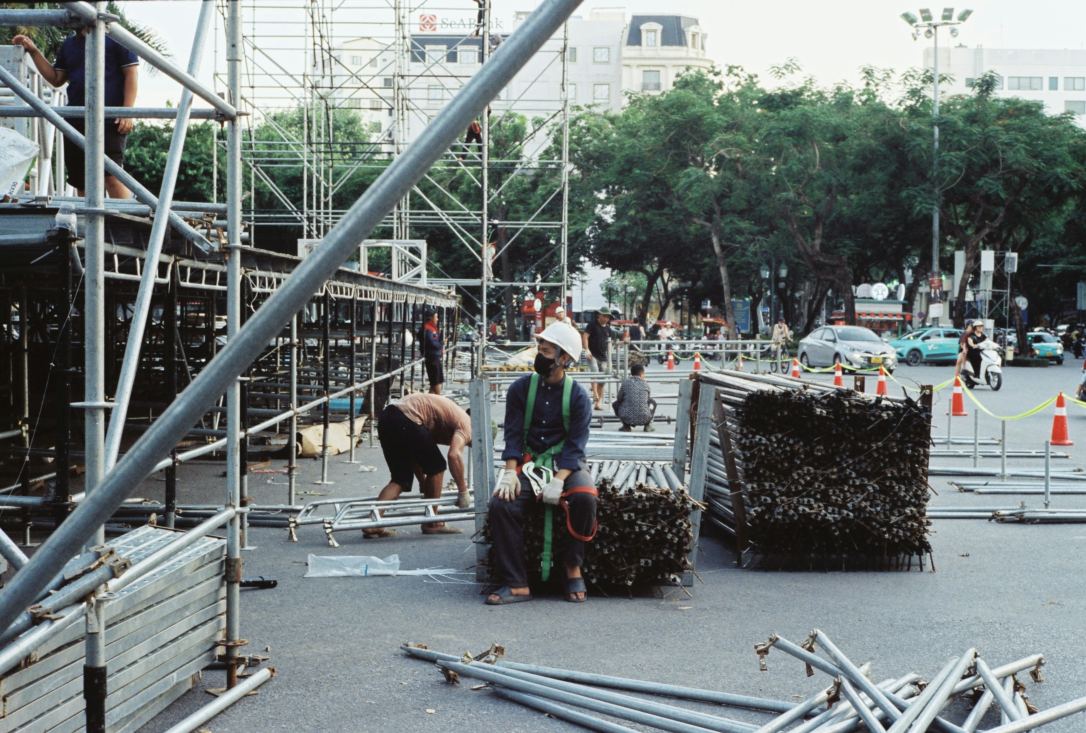 Workers setting up scaffolding in a city street.