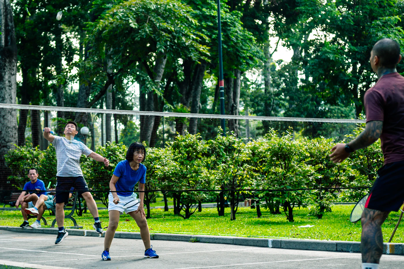 Freizeitspieler spielen gemeinsam Badminton in einem grünen Park