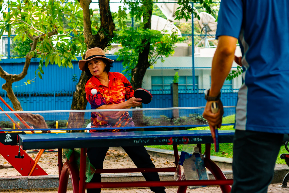 Two people playing table tennis outdoors