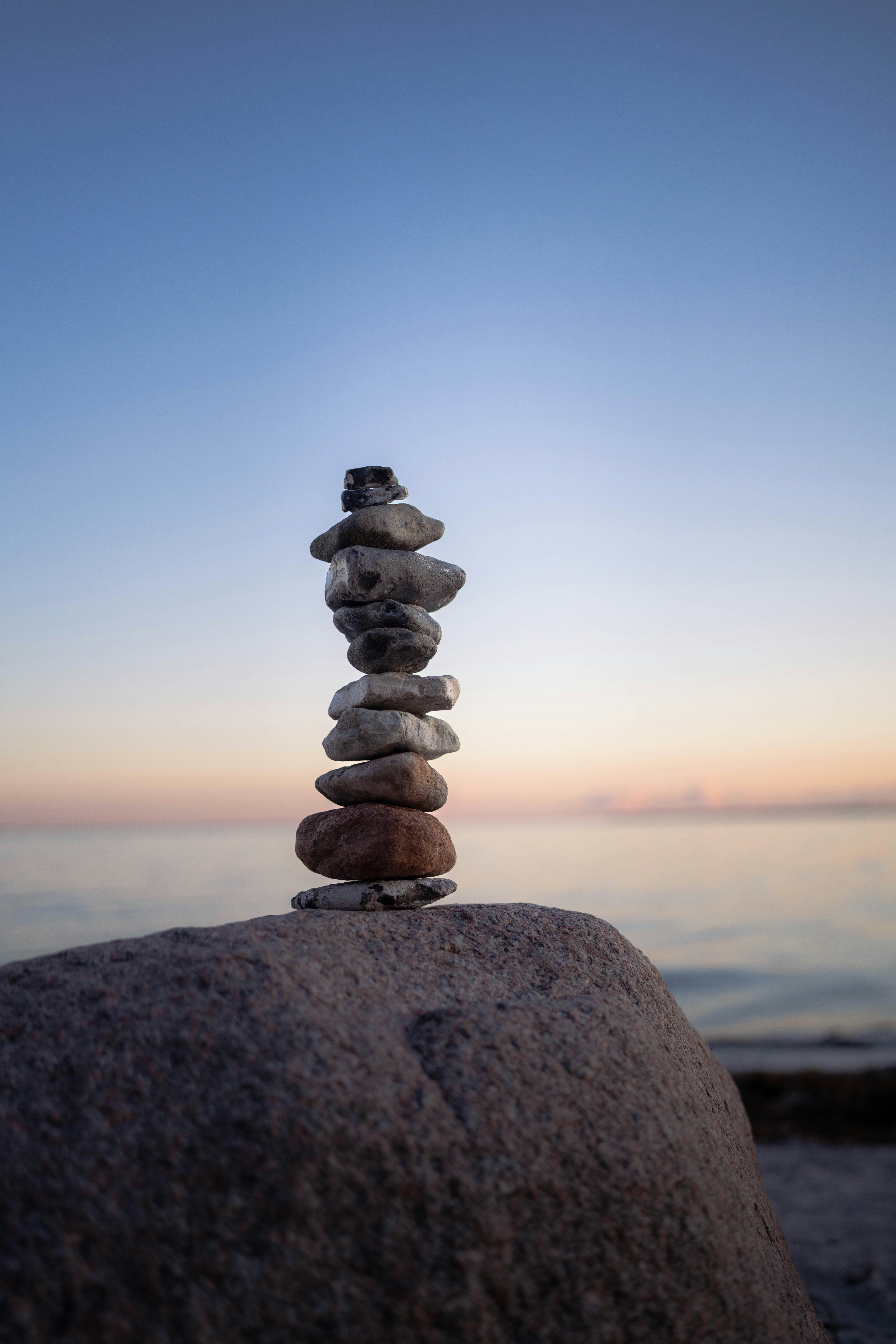 Stack of stones balanced on a rock at sunset.
