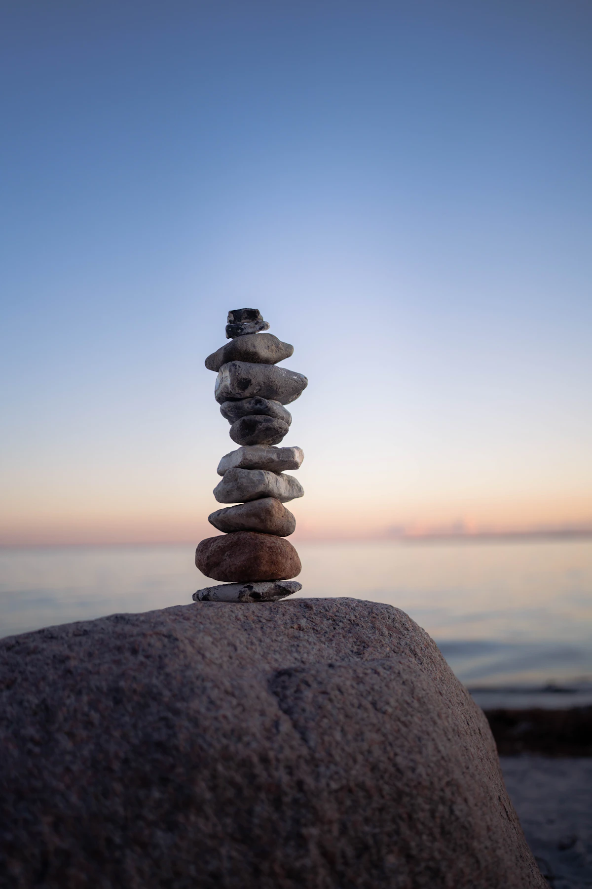 Stones balanced at sunset, symbolic of holding steady between opposites like day and night