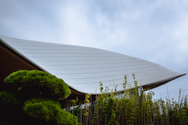 Modern building with curved roof and lush greenery