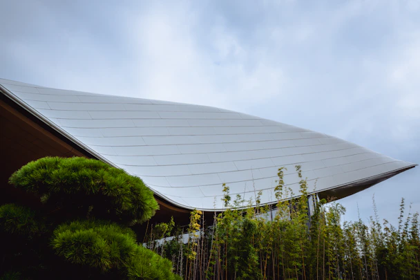 Modern building with curved roof and lush greenery