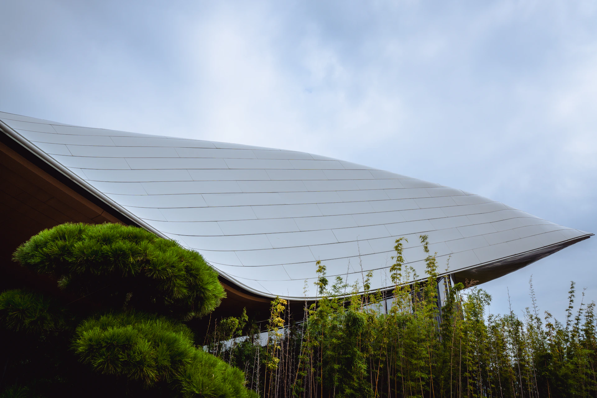 Modern building with curved roof and lush greenery