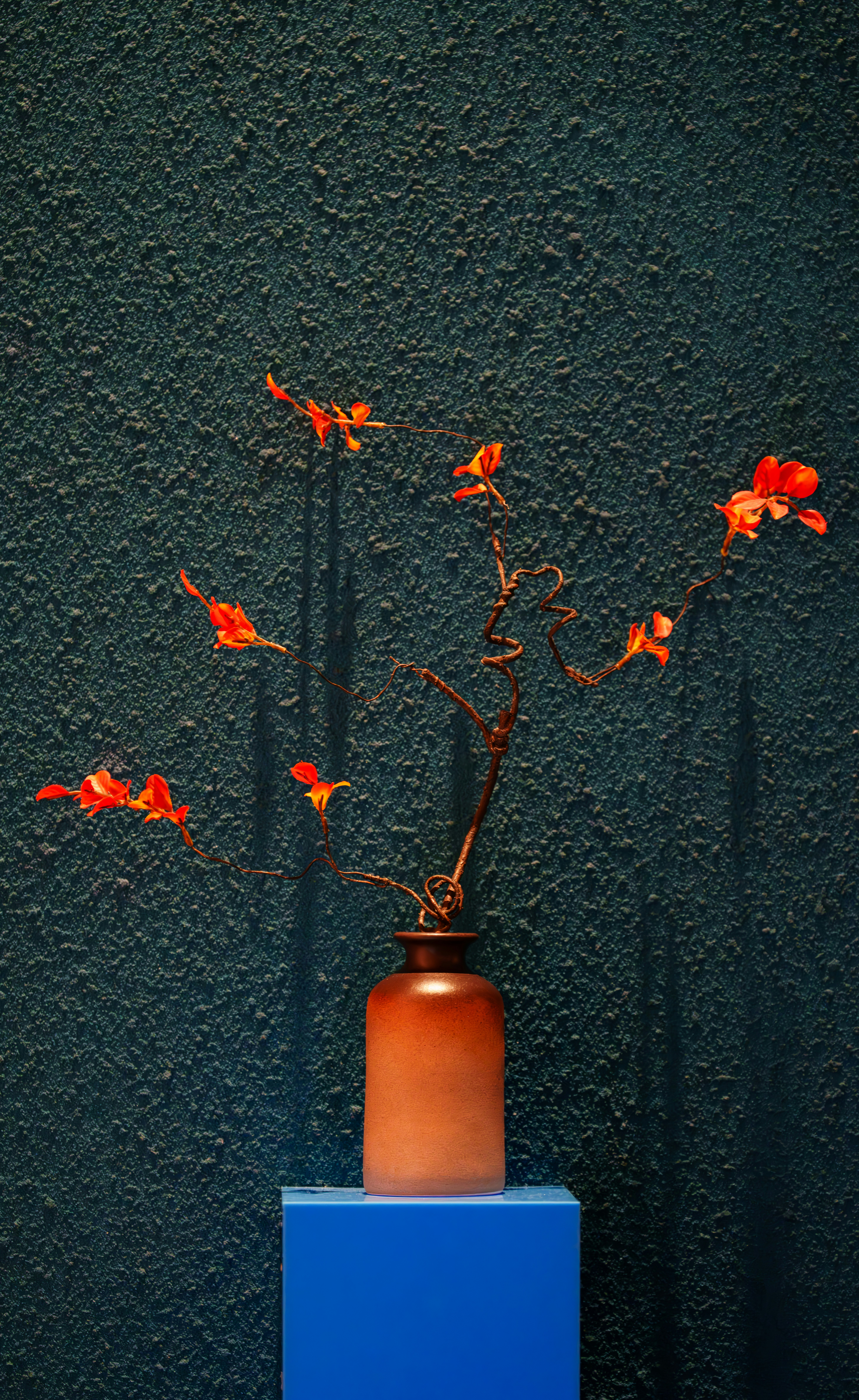 Orange flowers in a vase on a blue pedestal.