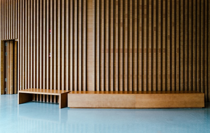 Modern wooden bench against slatted wall