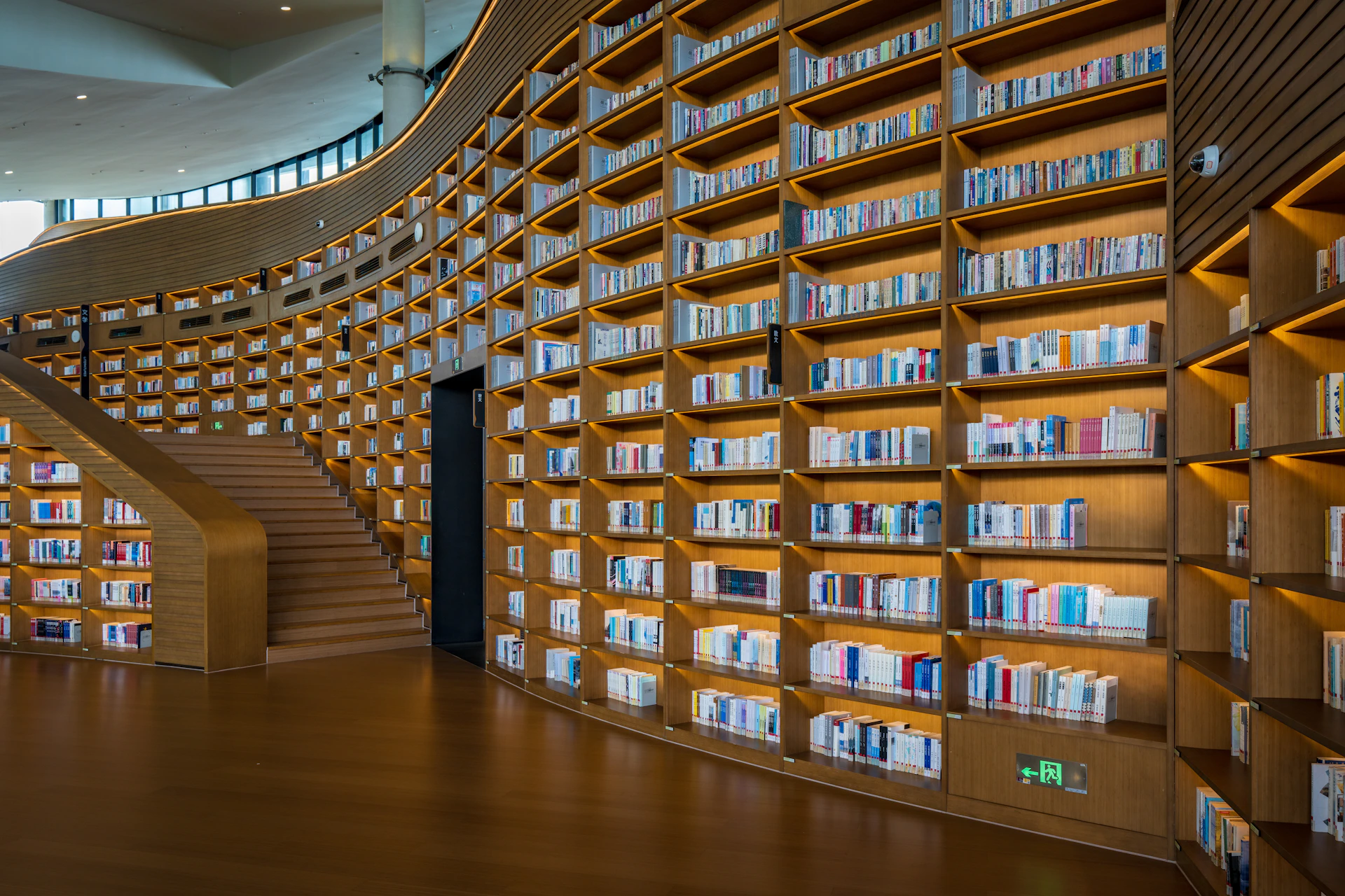 Curved wooden bookshelves filled with books in a library.