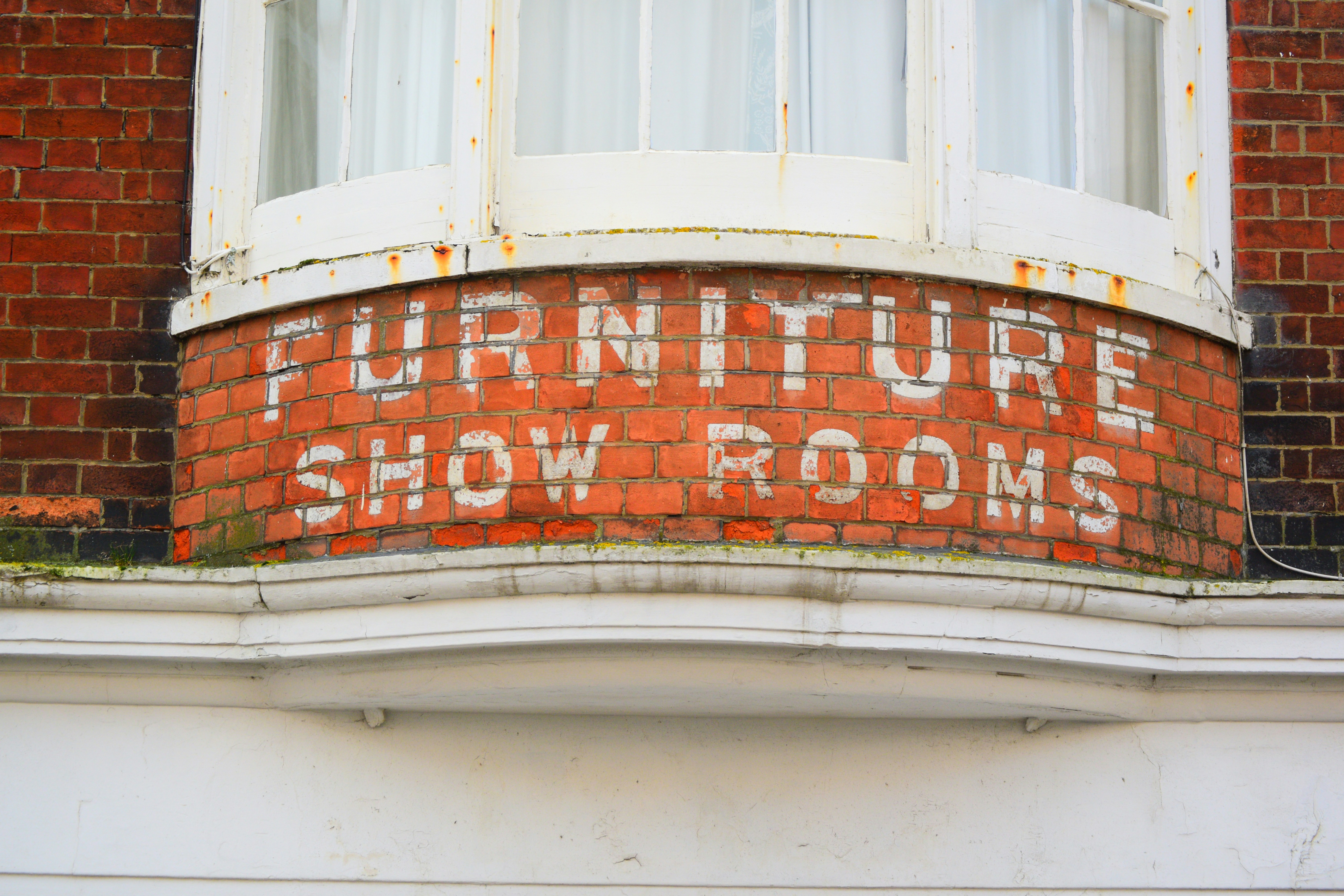Vintage sign for furniture show rooms on brick.