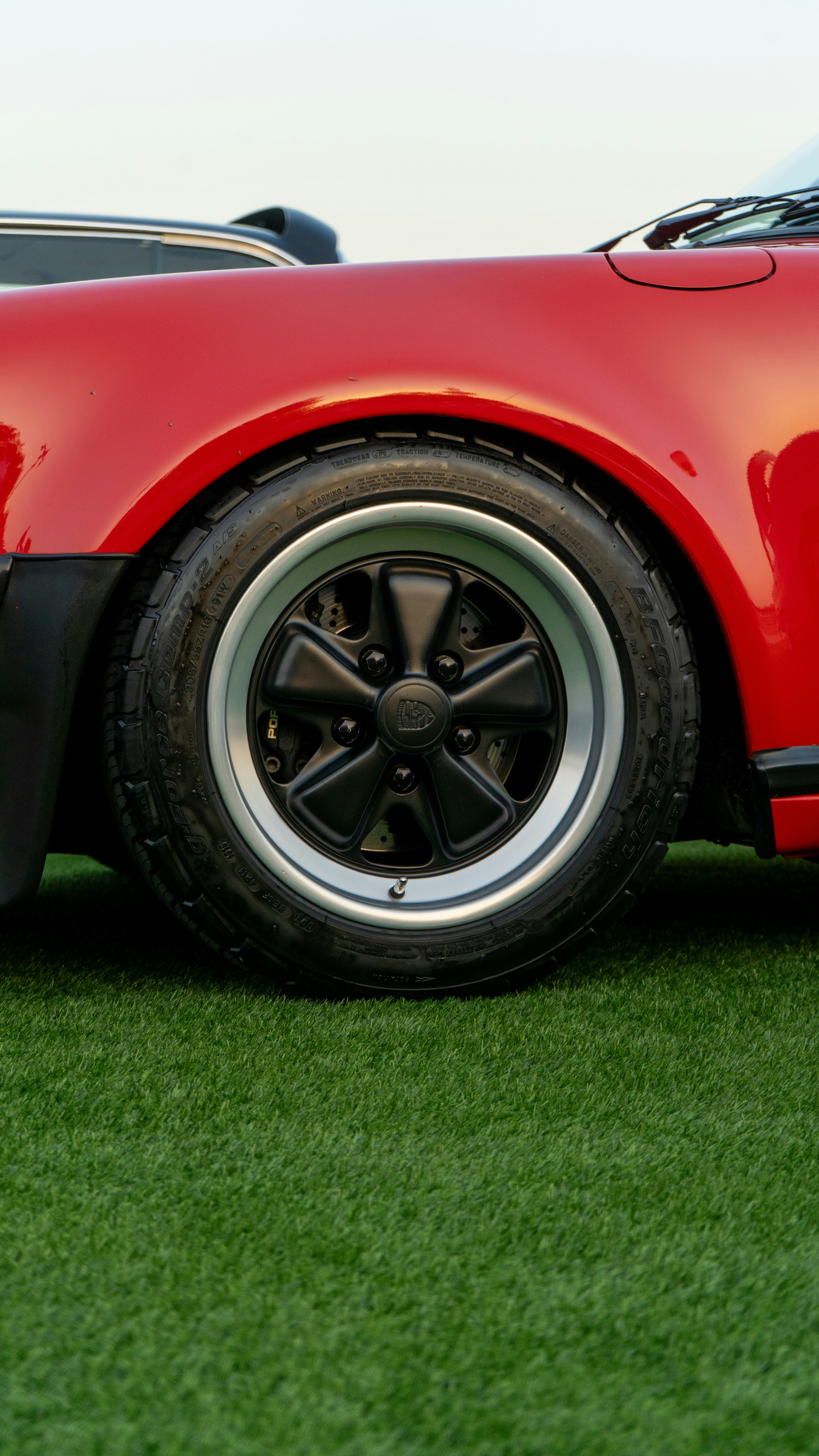 Close-up of a red car wheel on green grass